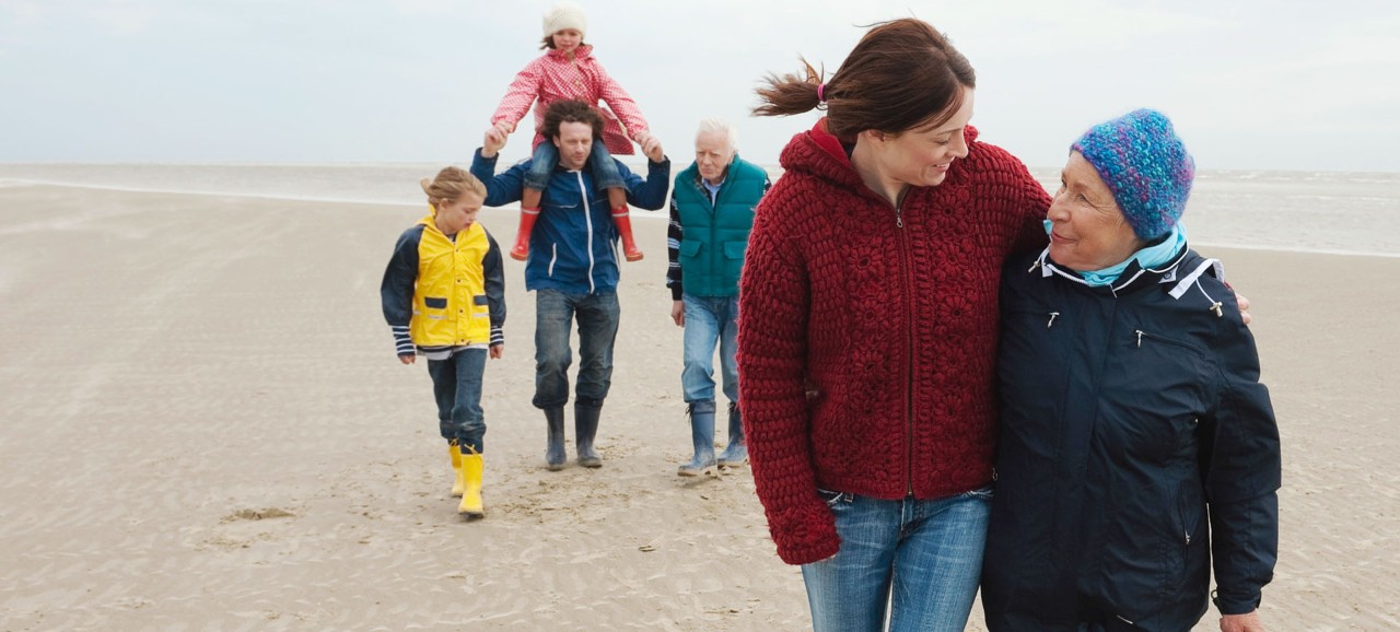 A younger and older woman walking together with two men and two children behind them.